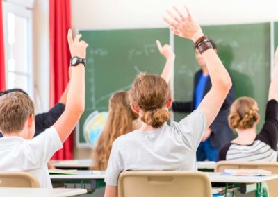 students with hands raised in a classroom