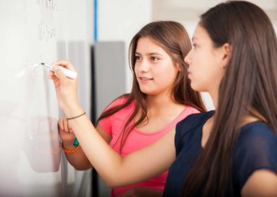 high school students writing on a white board during class