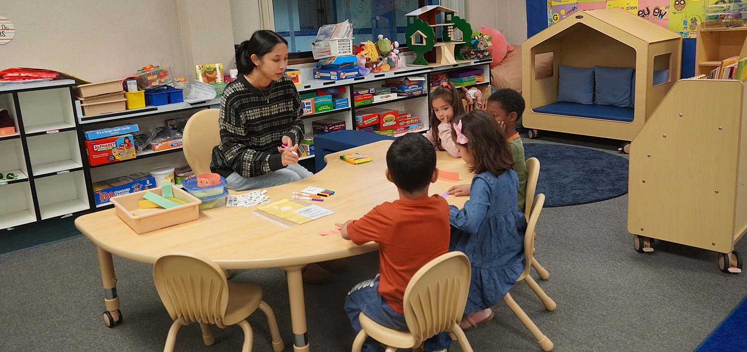 DSC09377 A teacher a a desk reading to children